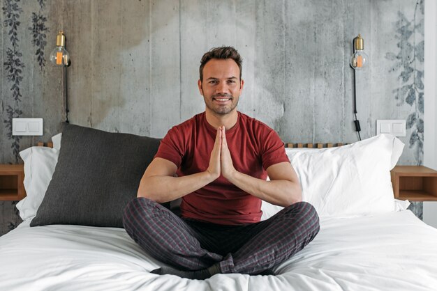 Uomo attraente sul letto meditando