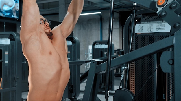 An attractive man bodybuilder doing strength exercises in the sports gym