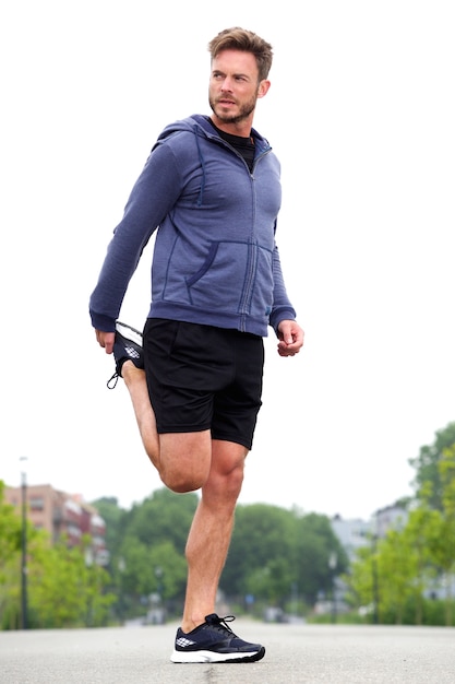 Attractive man doing stretch in street before run