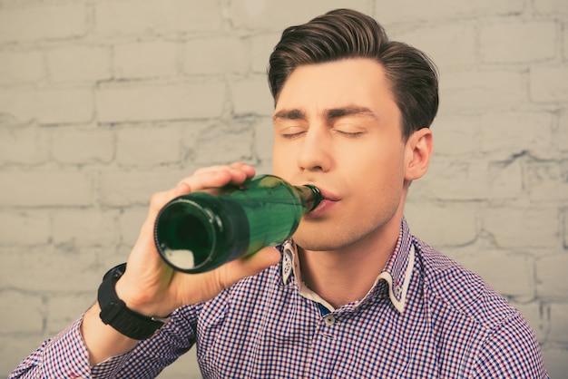 目を閉じてビールを飲む魅力的な男