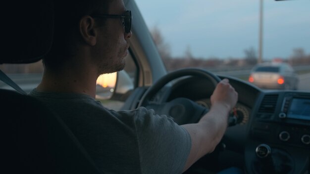 都市高速道路に沿って自動車を運転する魅力的な男