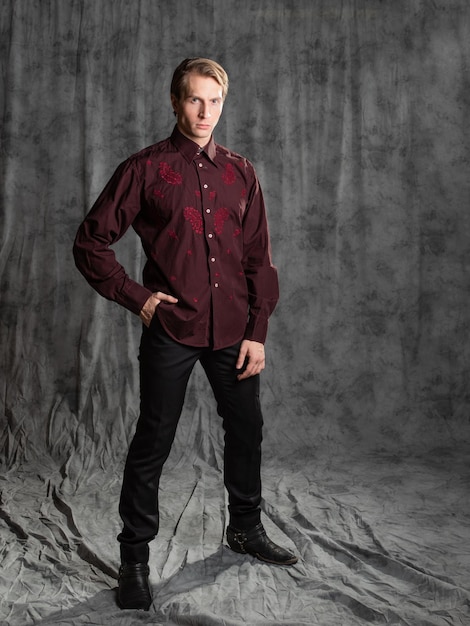 グレーの BA のスタジオで刺繍写真が付いたエレガントなスーツのバーガンディ シャツを着た魅力的な男性