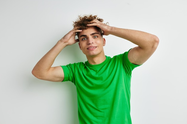 Привлекательный мужчина в зеленых футболках с эмоциями позирует на изолированном фоне