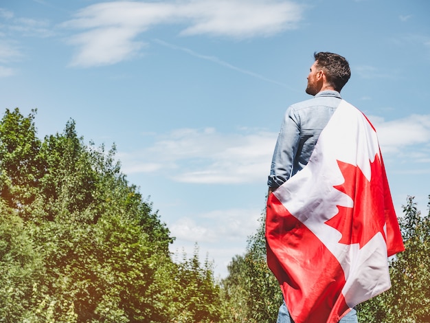 Foto uomo attraente che tiene bandiera canadese. festa nazionale