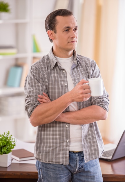 Attractive man holding a cup of tea and looking away.