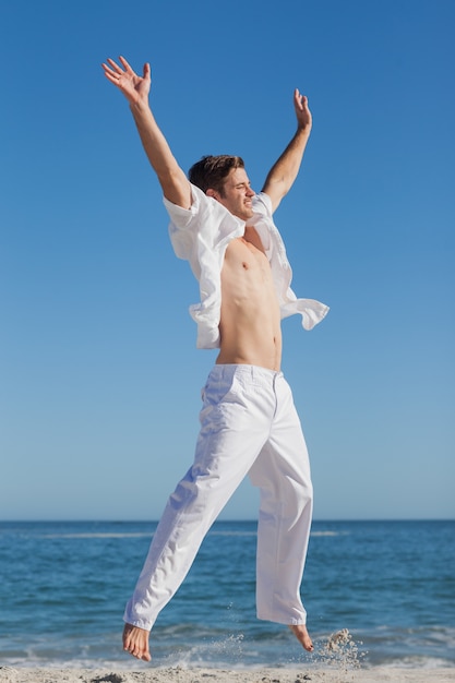 Attractive man jumping on beach