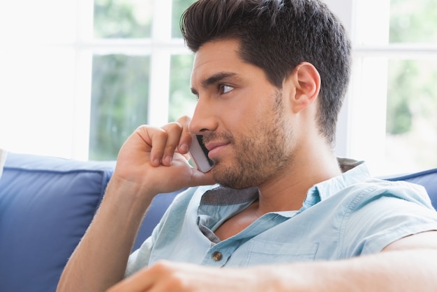 Attractive man making a call on the couch