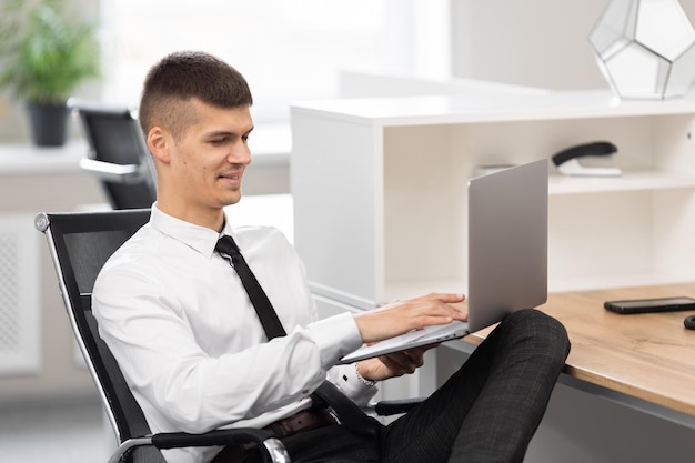 Attractive man in the office holding a laptop on his lap