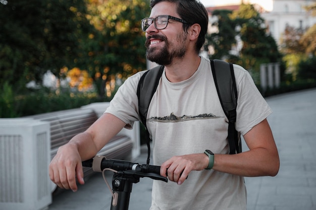 Attractive man riding a kick scooter at cityscape background