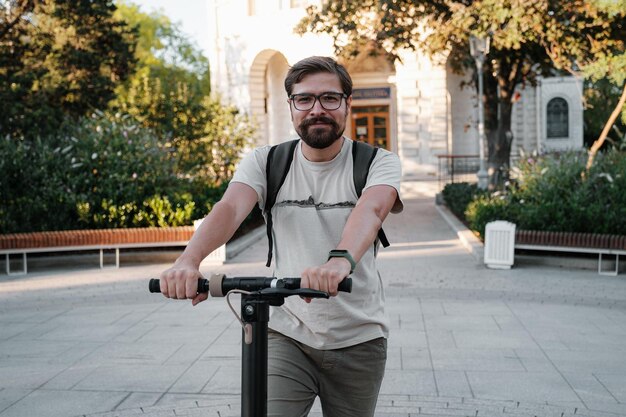 Attractive man riding a kick scooter at cityscape background