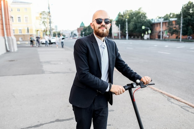 Attractive man riding a kick scooter at cityscape background