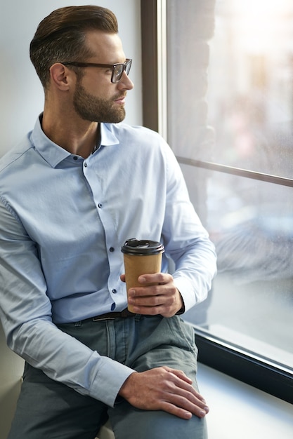 Attractive man sitting and posing on the window sill