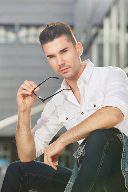 Photo attractive man staring sitting outside in city