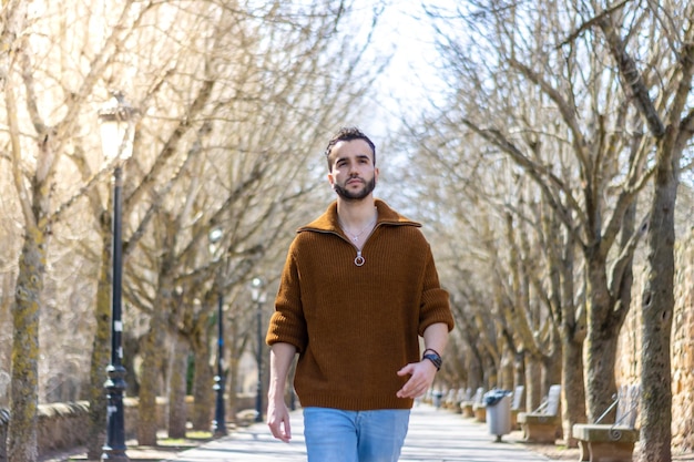 Attractive man on the street walking towards the camera Handsome bearded man in sweater walking down the street