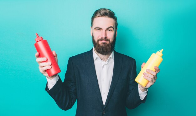 Attractive man in suite is holding two bottles in his hands