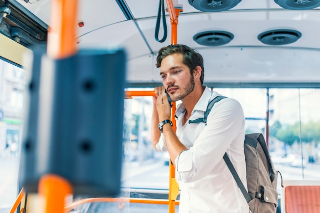 Uomo attraente che comunica sul telefono in bus pubblico