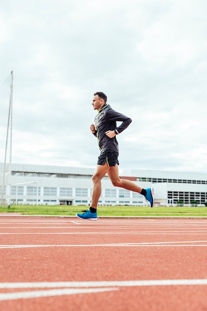 Atleta di pista uomo attraente in esecuzione su pista. è allo stadio