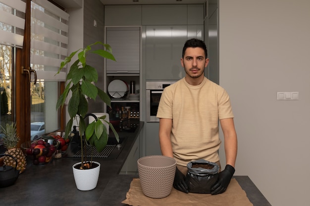 An attractive man transplanted an avocado seedling into a new, larger pot.