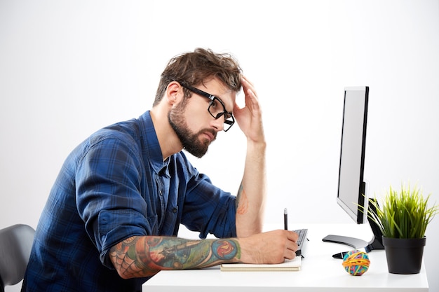 Attractive man wearing blue shirt sitting with laptop, freelance concept, portrait, online job, working process problems, overwork.