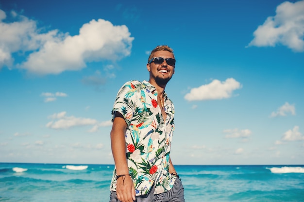 Attractive man wearing hawaiian shirt at the sea or the ocean background