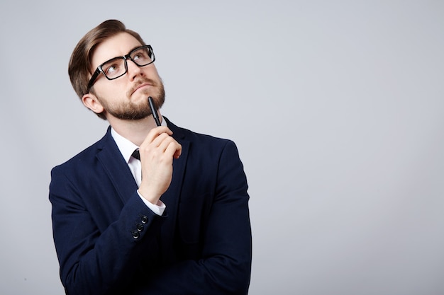 Attractive man wearing suit and glasses at studio thinking