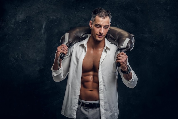 Photo attractive man in white opened shirt and with weight bag on his shouders is posing for photographer.