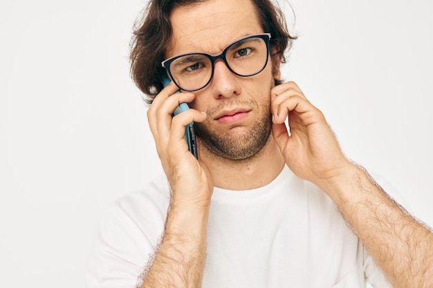 Attractive man in a white Tshirt communication by phone light background