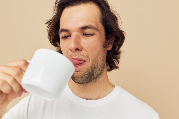 孤立した背景の手にマグカップと白いTシャツの魅力的な男