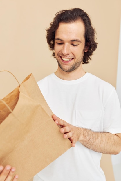 紙袋のライフスタイルを変えない白いTシャツの魅力的な男