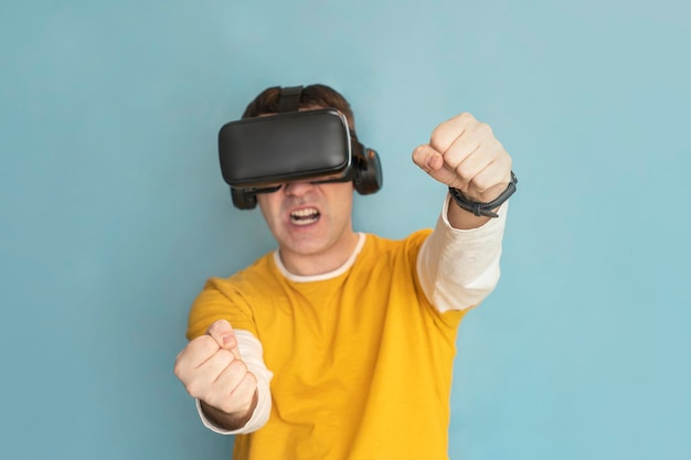 Привлекательный мужчина в очках виртуальной реальности платит автомобильный симулятор на синем фоне