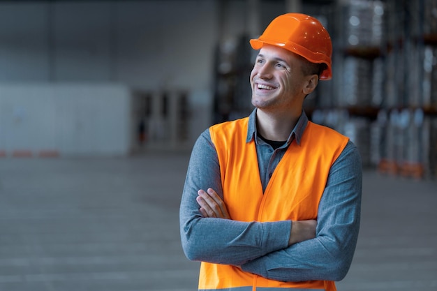 Foto uomo attraente ingegnere operaio che indossa abiti da lavoro e cappello rigido che guarda via con le braccia incrociate