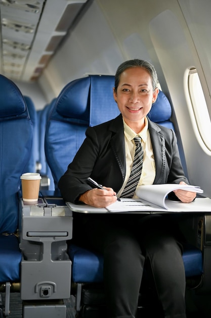 An attractive mature Asian businesswoman working on her business report during the flight