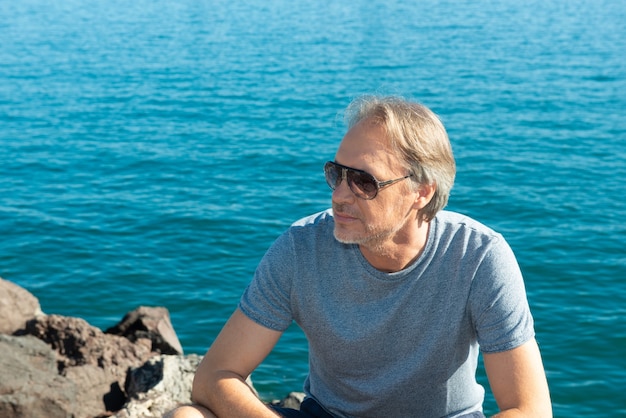 attractive mature man strolling along the marina in a city