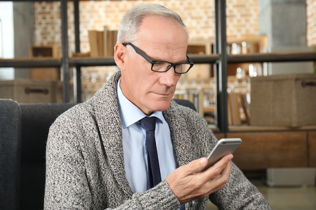 Attractive mature man with cell phone indoors