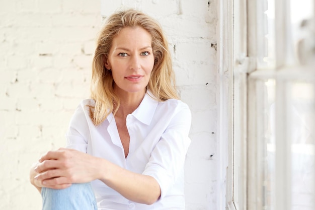 Attractive mature woman portrait while relaxing at the window