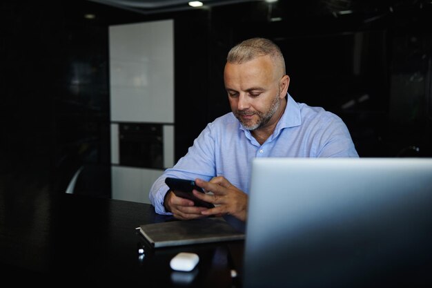 Attractive middle aged man using mobile phone, sitting at home office