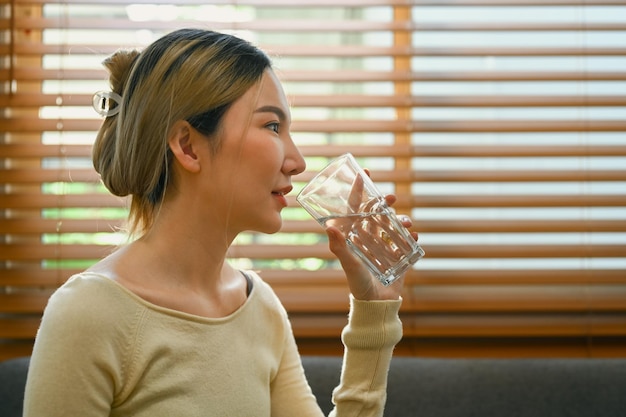 写真 ガラスから新鮮なミネラルウォーターを飲む魅力的なミレニアル世代の女性 水分補給と健康的なライフスタイルのコンセプト