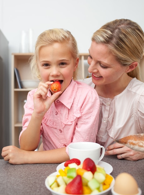 Attractive mother eating fruit with her daughter 