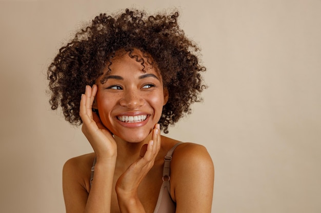 Attractive multiracial woman posing at camera over beige background