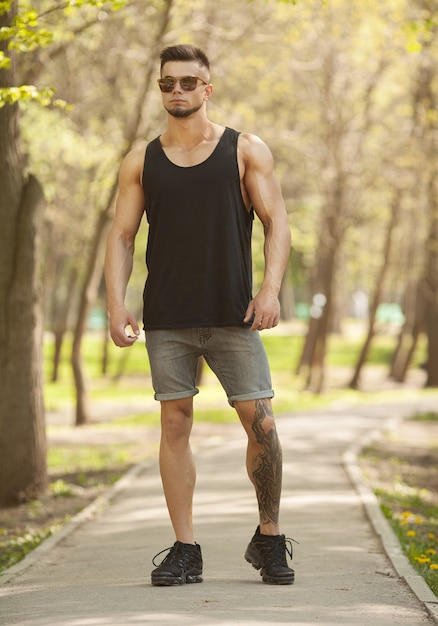 Attractive muscular man in city at nice summer day.