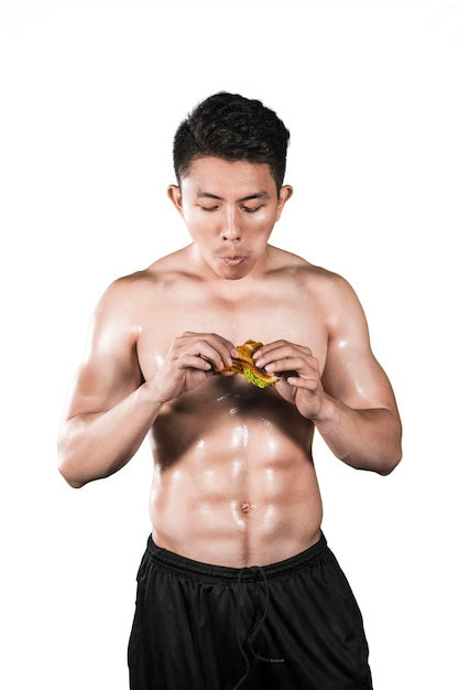 Attractive muscular man eating sandwich in studio