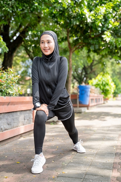 Attractive muslim asian woman strecth her leg during sport time outdoor in sunny day