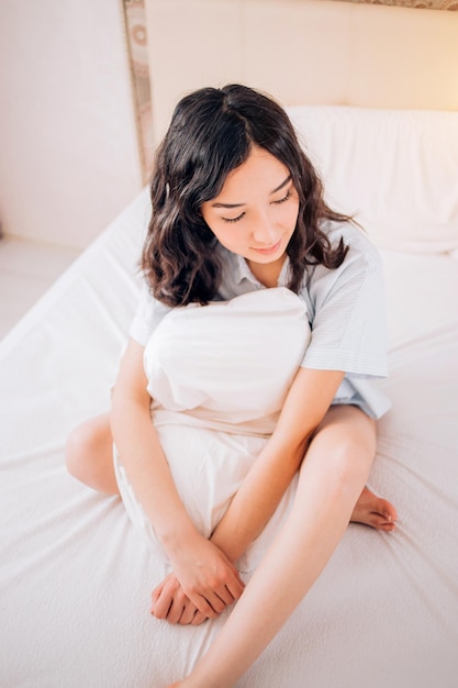 Attractive nice girl with fresh clean skin having rest under cream color blanket in comfortable bed in the morning, close up side view photo. Healthy sleep, free time, leisure and relaxation concept.