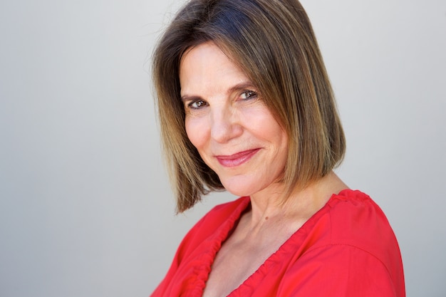 Attractive older woman smiling against gray background