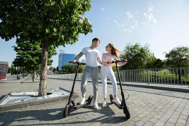 An attractive pair of lovers ride electric scooters and look at each other
