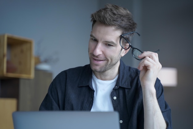 Attractive positive businessman in casual wear took off his glasses remotely working from home