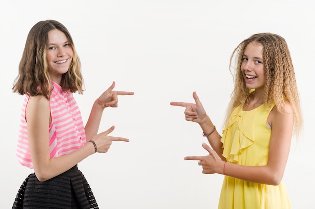 Attractive positive two teenage girls pointing her index finger away