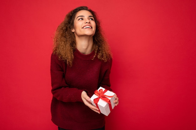 Attractive positivejoyful young brunette curly female person isolated over red background wall