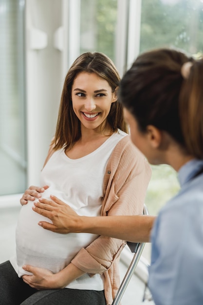 産婦人科医の診察を待っている間、看護師と話している魅力的な妊婦。