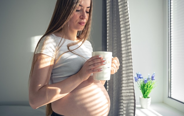 朝の窓辺でお茶を飲む魅力的な妊婦